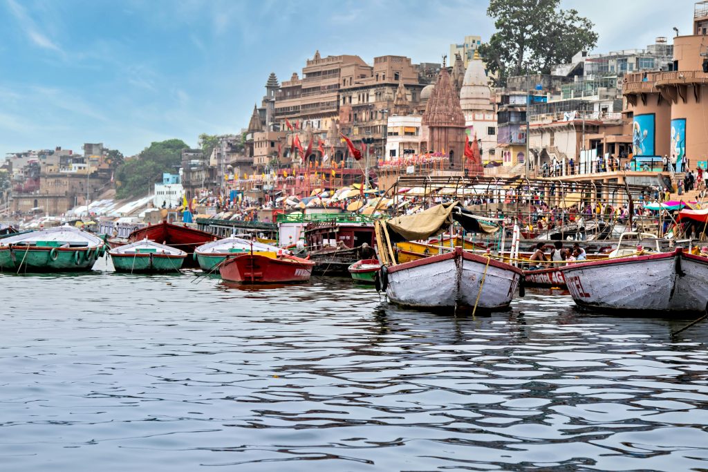 Vibrant boats aligned along Varanasi's iconic riverbank, showcasing urban life by the Ganges. Top 5 Places to Visit in Uttar Pradesh in Summer
